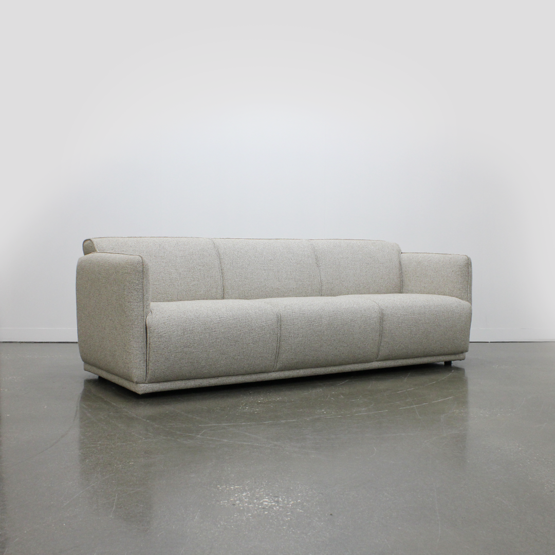 Beige sofa on a gray floor with a white wall background